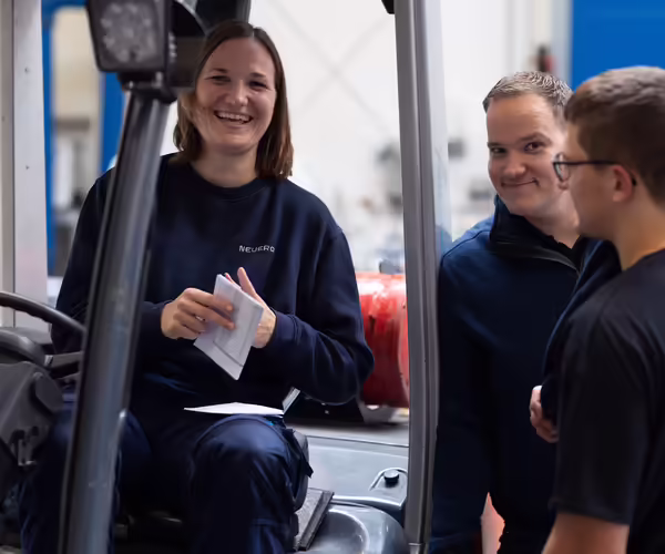 Drei NEUERO Mitarbeitende stehen fröhlich zusammen.