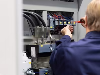 Ein elektrischer Schaltkasten wird sorgfältig von einem NEUERO Mitarbeiter verkabelt.