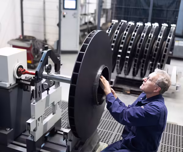 Ein NEUERO Mitarbeiter überprüft ein Metallbauteil.