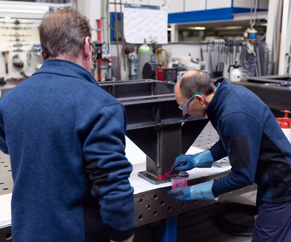 Zwei NEUERO Mitarbeiter arbeiten an einem Maschinenbauteil.