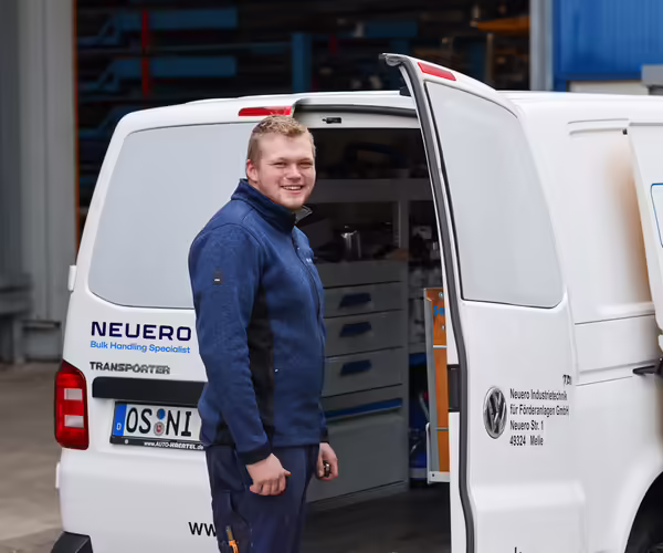 Ein NEUERO Mitarbeiter steht gut gelaunt vor einem geöffneten Lieferwagen.