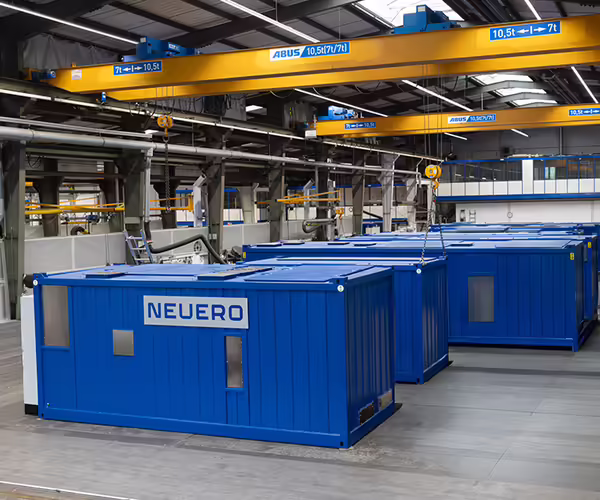 Mehrere blaue NEUERO Container stehen in einer Industriehalle.