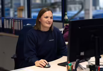 NEUERO Mitarbeiterin Lena Nowak sitzt konzentriert an Ihrem Bildschirmarbeitsplatz.