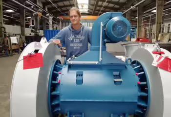 NEUERO Mitarbeiter Robert Wolf steht hinter einem grossen Maschinenbauteil.