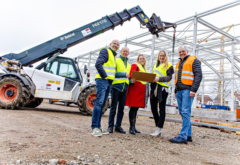 5 Personen in Warnwesten stehen gut gelaunt auf einer Baustelle bei Melle.